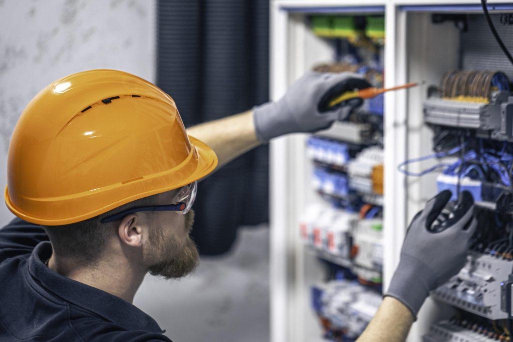 Male electrician working in a switchboard with fuses.